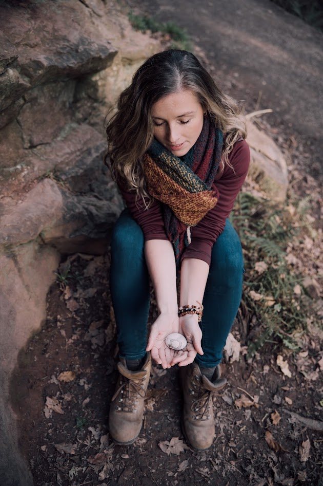 Libby sitting on a sandstone ledge, eyes closed, holding a small pebble in her open hands
