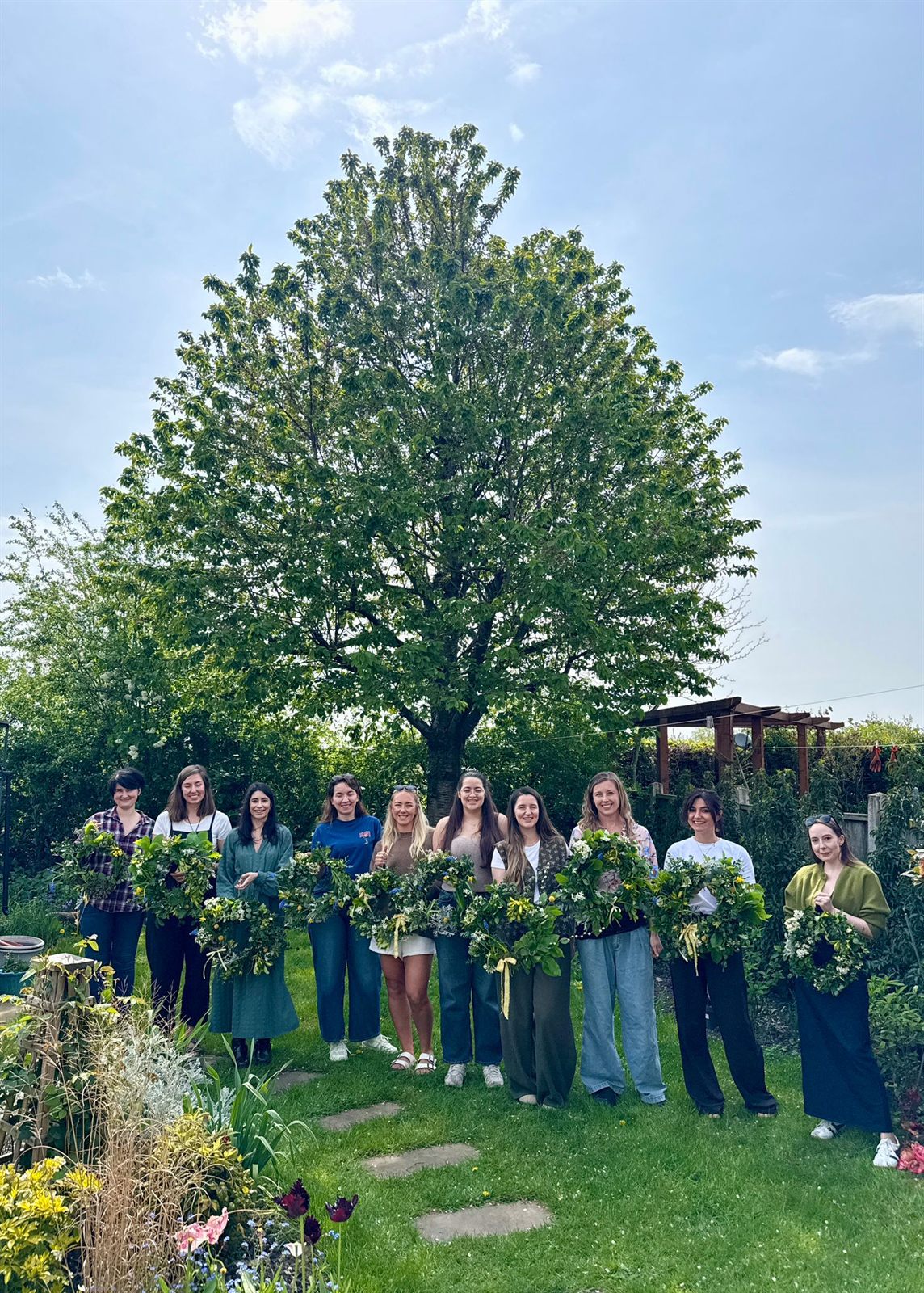 A group holding spring wreaths in a garden