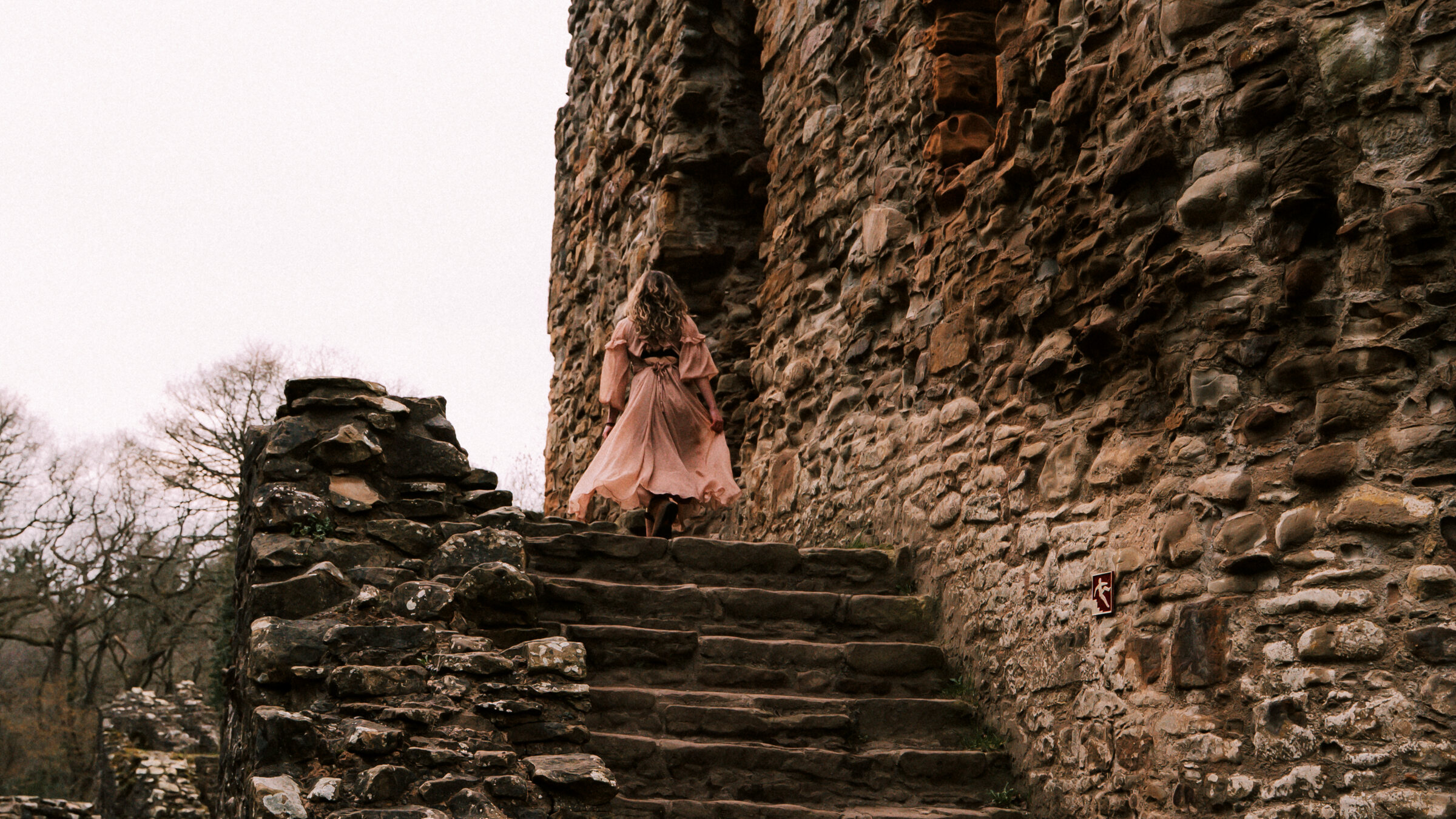Libby climbing the steps of a ruined castle wall