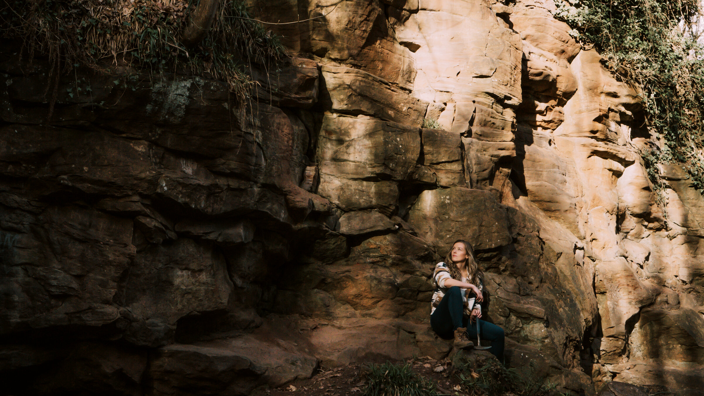 Libby at the foot of a sunlit sandstone outcrop