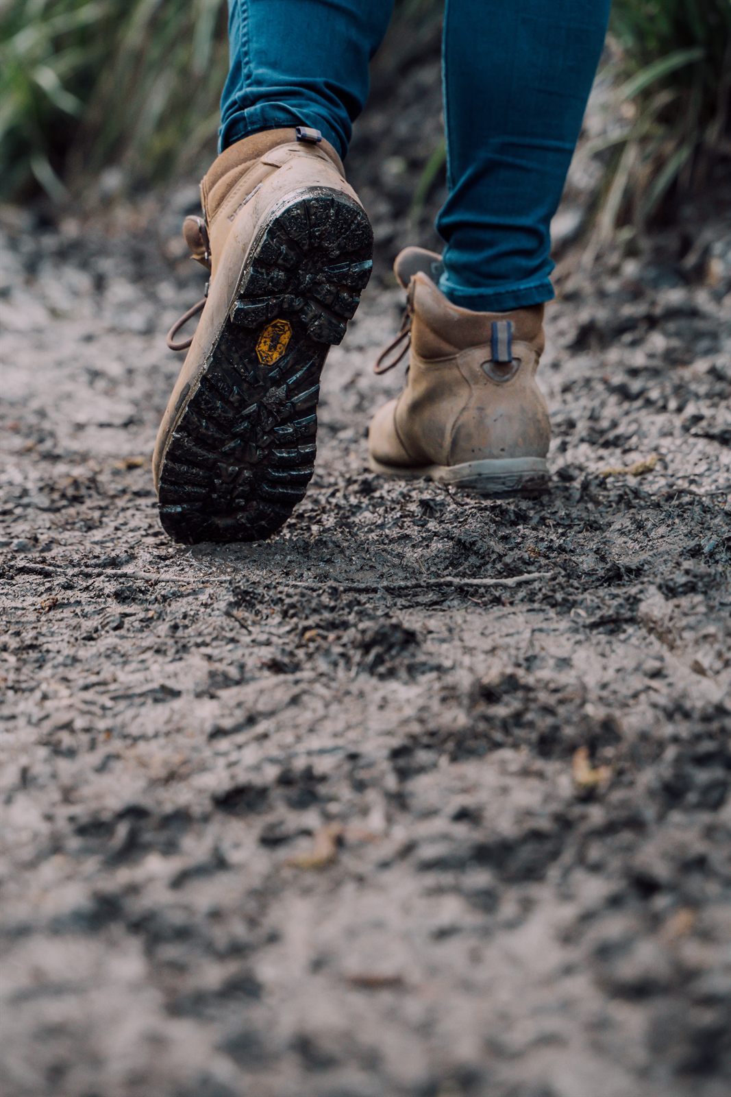 Muddy walking boots mid-stride on a woodland path