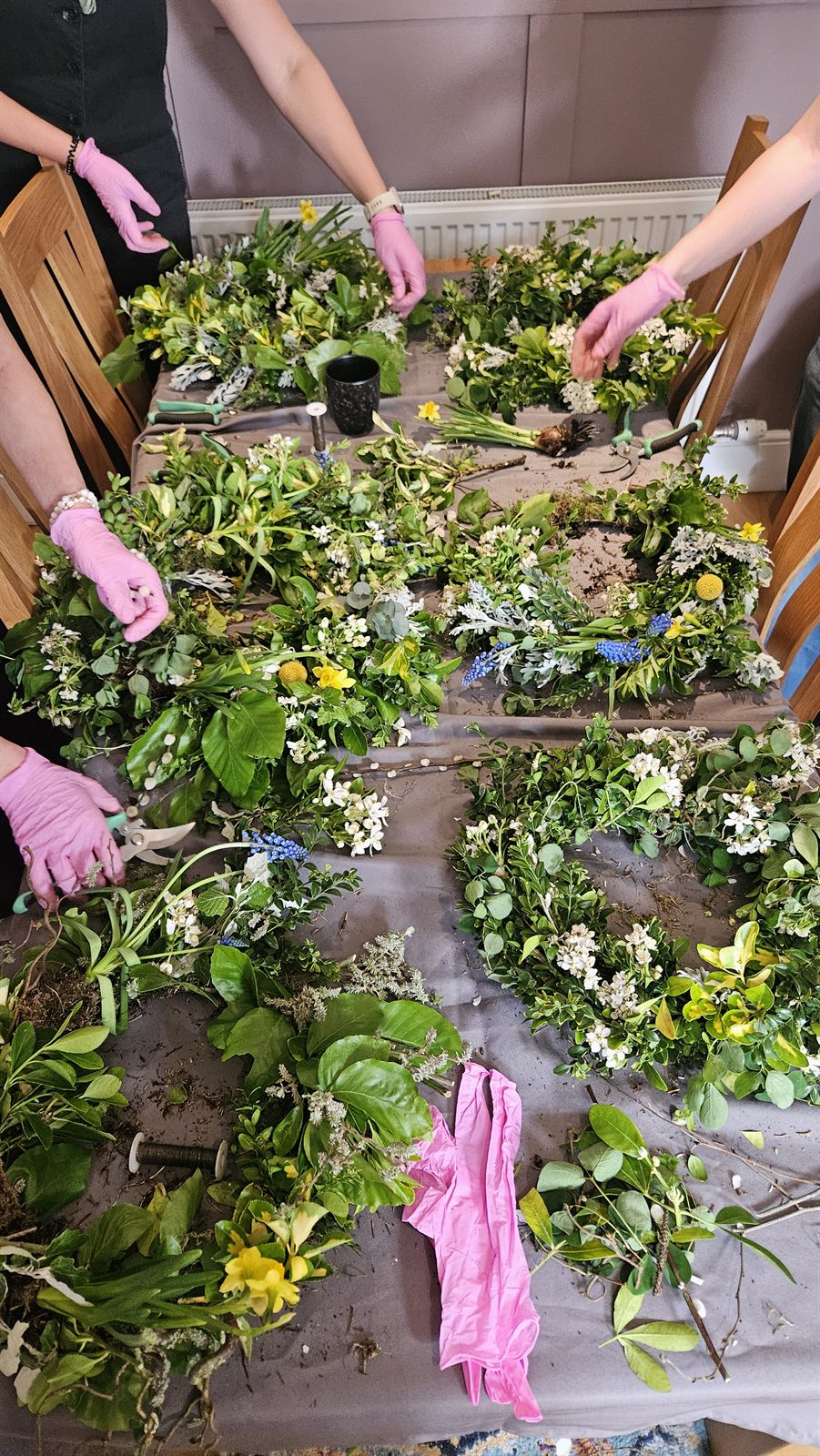 A table laid with seasonal foliage and flowers for wreath making